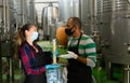 Two winemakers checking winemaking process at factory