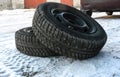 Two winter tires on disks lie on the snow-covered ground next to Royalty Free Stock Photo