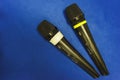 Two wireless microphones lie on a blue desk. Radio microphones for carrying out of an event and conferences close up. Royalty Free Stock Photo