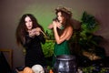 Two witches with rats in their hands pose against a dark background