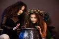 Two witches with tousled hair brew a potion in a cauldron with rats, halloween concept Royalty Free Stock Photo