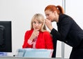 Two woman colegues gossip in office