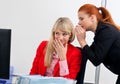 Two woman colegues gossip in office