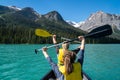 Two woman hold up paddle oars while canoeing on Emerald Lake in the Canadian Rockies