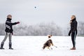 Two woman playing with their dog in the snow, winter season walk Royalty Free Stock Photo