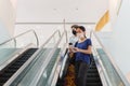 Two woman in protective mask with shopping bags and mobile phone standing on escalator in shopping mall. Royalty Free Stock Photo