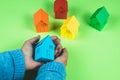 Two woman`s hands hold a blue house. Green background Royalty Free Stock Photo