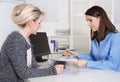 Two woman sitting at desk talking about terms and conditions. Royalty Free Stock Photo