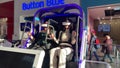 Two woman is sitting in an electric blue virtual reality chair
