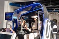 Two woman is sitting in an electric blue virtual reality chair