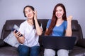 two woman using laptop computer and listening to music in headphones with moblie on sofa at home Royalty Free Stock Photo