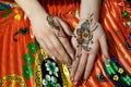 Two womans hands mehendi picture orange bright fabric with pleats