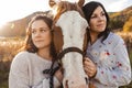 Two Womans with her horse at sunset, autumn outdoors scene Royalty Free Stock Photo
