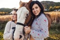 Two Womans with her horse at sunset, autumn outdoors scene Royalty Free Stock Photo