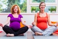 Two women advanced in pregnancy meditate during antenatal class
