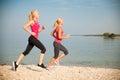 Two women athlets running on the beach - early morning summer w Royalty Free Stock Photo