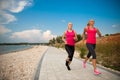 Two women athlets running on the beach - early morning summer w Royalty Free Stock Photo