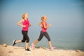 Two women athlets running on the beach - early morning summer w Royalty Free Stock Photo