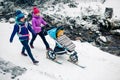 Two women with baby stroller enjoying winter in forest, family time Royalty Free Stock Photo