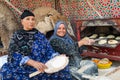 Two women baking traditonal Al-Shamsi bread in wood-fired clay oven