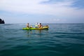 Two women in bikini or swimwear are enjoying canoe or kayak on Andaman Sea with speedboat, island and clear blue sky background Royalty Free Stock Photo