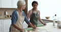 Two women blab while flattening dough in the kitchen