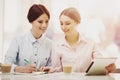 Two Women in Cafeteria with Coffe and Tablet. Royalty Free Stock Photo