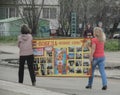 Two women carry a signboard with inscription meaning Victory Is a Great Word. Cloudy spring view.