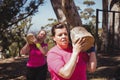 Two women carrying a heavy wooden log during obstacle course Royalty Free Stock Photo