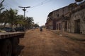 Two women carrying large bags on their heads and crossing a dirt street near the port of Bissau.