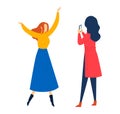 Two women in colorful dresses, one dancing joyfully another taking a photo. One celebrates, while the other captures the