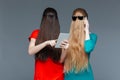 Two women with covered faces using tablet and cell phone Royalty Free Stock Photo