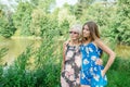 Two women of different generations are near a pond in the summer. Mother and daughter hugging. Grandmother and granddaughter. Royalty Free Stock Photo