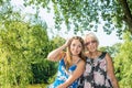 Two women of different generations sitting on a bench near a pond in the summer Royalty Free Stock Photo