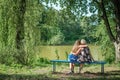 Two women of different generations sitting on a bench near a pond in the summer. Mother and daughter hugging. Grandmother and gran Royalty Free Stock Photo