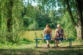 Two women of different generations sitting on a bench near a pond in the summer. Mother and daughter hugging. Grandmother and gran Royalty Free Stock Photo