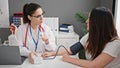 Two women doctor and patient measuring pulse using tensiometer at clinic