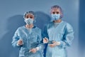 Two women doctors surgeons standing and looking at the camera on blue bakcground Royalty Free Stock Photo