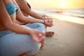 Two women doing group meditation on the beach on sunrise. Female friends doing yoga padmasana or lotus asana sitting on Royalty Free Stock Photo