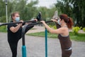 Two women doing stretching exercises wearing medical masks outdoors. Royalty Free Stock Photo