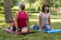 Two women doing yoga in a park. They do backward leg stretches