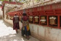 Two women dress in Pilgrims suit rotating praying wheels