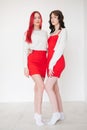 Two women dressed in identical red dresses and white sweaters. Lesbian intimacy. White background. Royalty Free Stock Photo