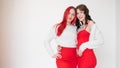 Two women dressed in identical red dresses and white sweaters. Lesbian intimacy. White background. Royalty Free Stock Photo