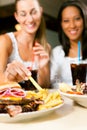 Two women eating hamburger and drinking soda Royalty Free Stock Photo