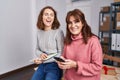 Two women ecommerce business workers writing on notebook using smartphone at office Royalty Free Stock Photo