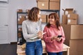 Two women ecommerce business workers writing on notebook using smartphone at office Royalty Free Stock Photo