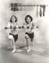 Two women exercising with dumbbells at gym