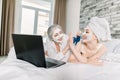 Two women with facial masks, pretty young girl wrapped in towel and her senior attractive grandmother, having fun while
