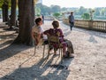 Two women friends chat on park chairs in the Jardin de Luxembourg at sunset, Paris, France